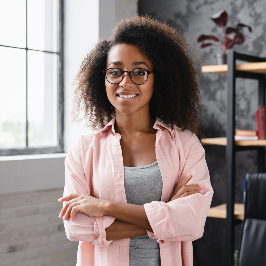 Office worker, young african student businesswoman freelancer tutor looking at camera with arms crossed while standing at home office