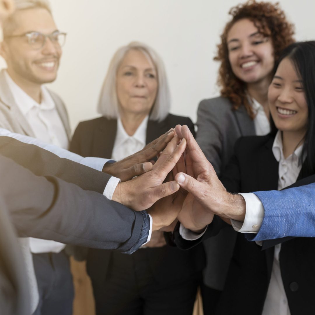 group of business workers of different ages put their hands together