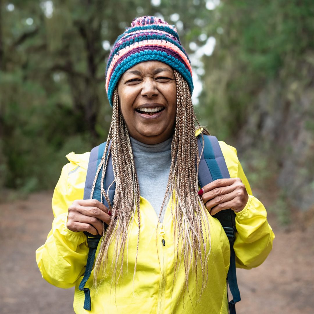 Happy Afro senior woman having a walk in the woods - Adventure and travel people concept